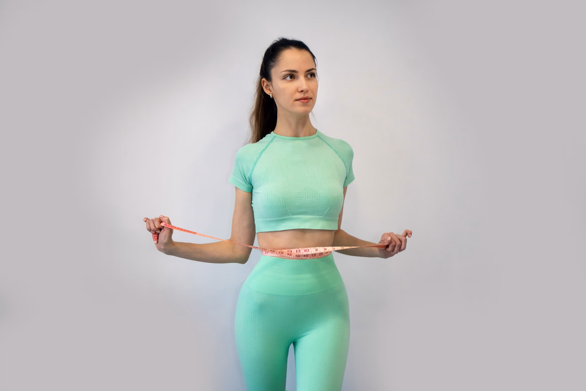 Young Slender Woman In sportswear Measuring Her Waist
